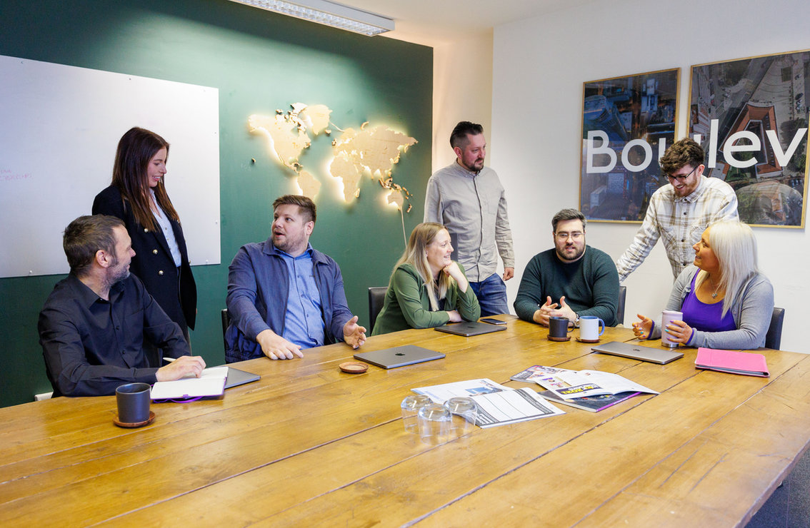 The Boulevard team meeting around a table in the office